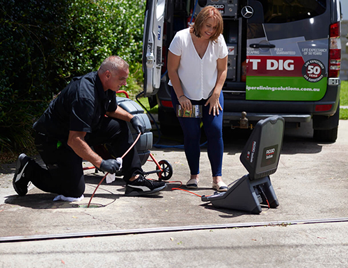 pipe relining solutions technician inspecting drain with customer